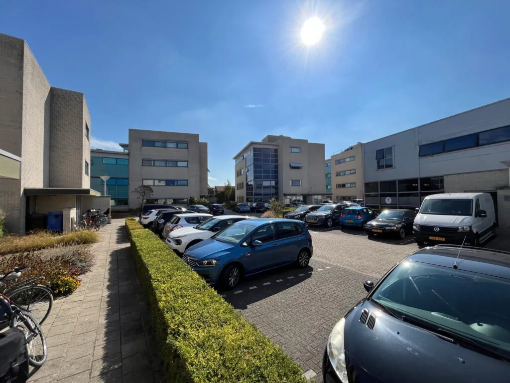 Parkeerterrein met geparkeerde auto's bij moderne kantoorpanden in de wijk Leidsche Rijn op een zonnige dag.
